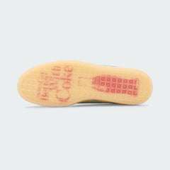 View of the outsole of the Puma Suede x Coca-Cola Unisex white trainers, showing the durable rubber cupsole and tread pattern.