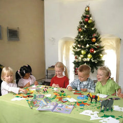 Children playing with toys at a table in front of a Christmas tree.