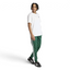 The Collegiate Green SST pants, highlighting the slim fit and the high-contrast white 3-Stripes running down the leg.