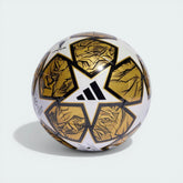 Side profile of the White and Gold UCL Club ball, highlighting the metallic star panels and black lion-inspired graphics.