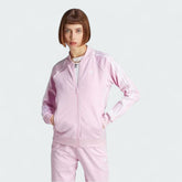 Adidas Adicolor Classics Superstar Track Jacket in orchid fusion pink, front view showing full zip, stand-up collar, white 3-Stripes on sleeves, and embroidered Trefoil logo.