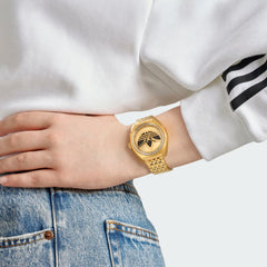 Adidas Edition One Watch in gold metallic on a person's wrist, showcasing its elegant fit and bold Trefoil design.