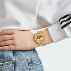 Adidas Edition One Watch in gold metallic on a person's wrist, showcasing its elegant fit and bold Trefoil design.