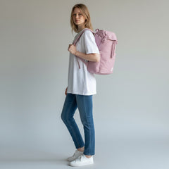 Woman holding a pink backpack against a plain background