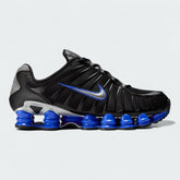 Nike Shox TL men's sneakers in black and metallic silver, side profile showing the full-length Nike Shox columns in the sole and the supportive upper.
