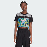 Woman wearing the Adidas x Her Studio London Cropped Tee with a multicolour floral print, demonstrating its stylish fit and cropped length.