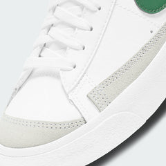 Close-up zoom on the front of the Nike Blazer Mid '77 Juniors' white trainers, showing the perforated toe box, lacing system, and texture of the leather upper.
