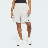 Side profile of the Dark Grey Heather Nike fitness shorts, showing the relaxed fit and the subtle black embroidered Swoosh on the lower left leg.