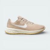 Side profile of the Nike Revolution 6 in Sand Drift, showing the white Swoosh, Topaz Gold accents, and the clean white foam midsole.