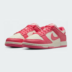 Angled view of two Nike Dunk Low Next Nature Women's trainers in pink and white, side by side, showcasing their clean aesthetic and retro style.