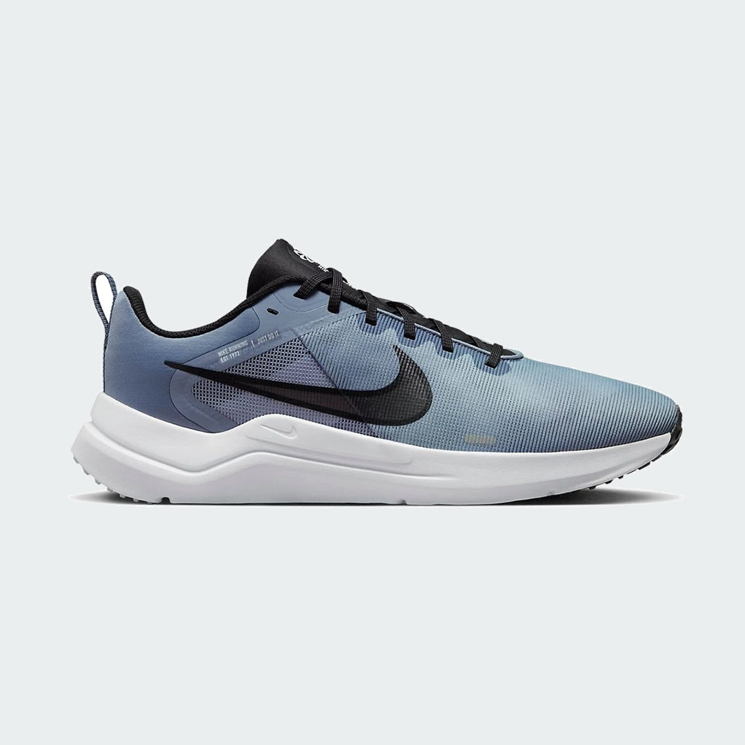 Nike Downshifter 12 Men's training shoes in grey with black and blue accents, side profile showing mesh upper, foam cushioning, and Nike Swoosh.