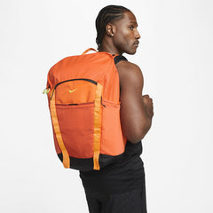 Nike Hike Backpack (27L) in safety orange worn by a person, angled view showcasing its versatile design for school, travel, or day hiking.