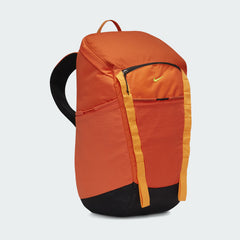 Side profile of the Nike Hike Backpack (27L) in safety orange, highlighting a stretchy side pocket and bottom loops for trekking poles.