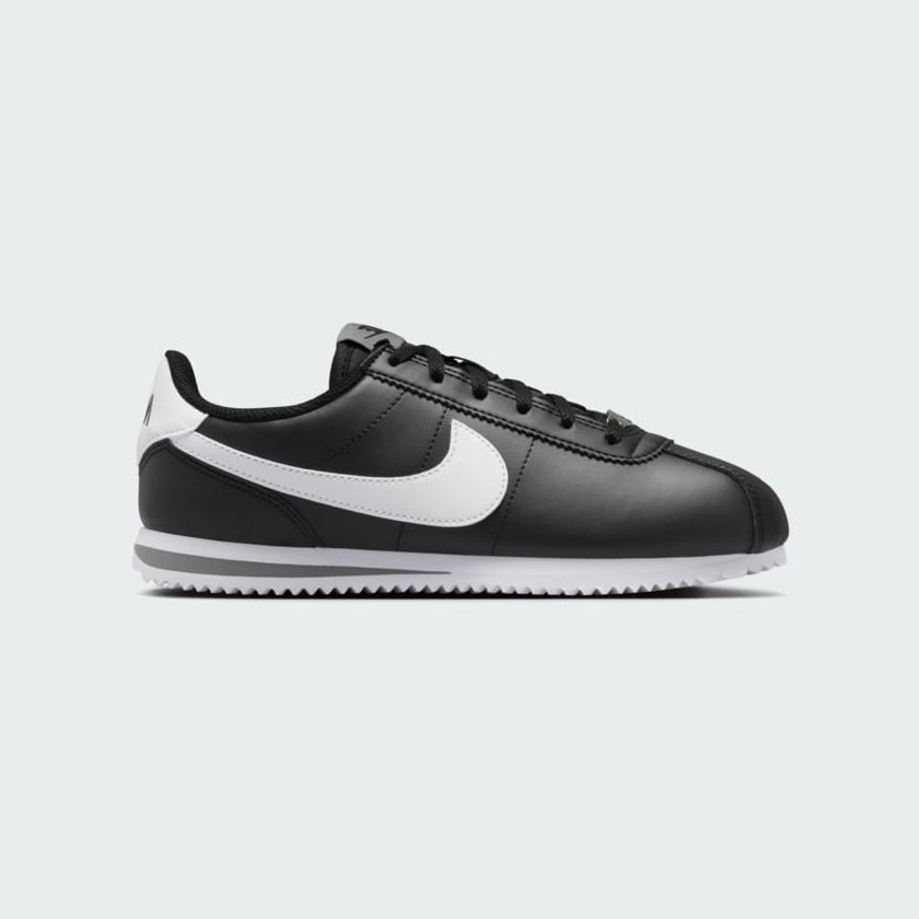Nike Cortez Juniors' trainers in black with a white Nike Swoosh and white midsole, side profile showing classic silhouette.