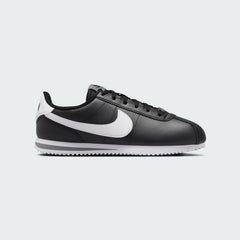 Nike Cortez Juniors' trainers in black with a white Nike Swoosh and white midsole, side profile showing classic silhouette.