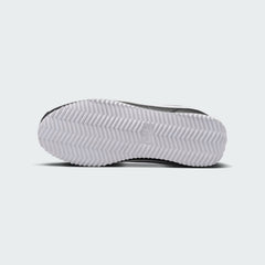 View of the outsole of the Nike Cortez Juniors' black trainers, showing the durable rubber sole with herringbone traction pattern.