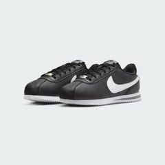 Angled view of two Nike Cortez Juniors' black trainers, side by side, showcasing their iconic design and clean aesthetic.