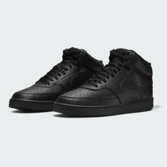 Angled view of two Nike Court Vision Mid Next Nature Men's black shoes, side by side, showcasing their clean, monochromatic aesthetic and mid-top height.
