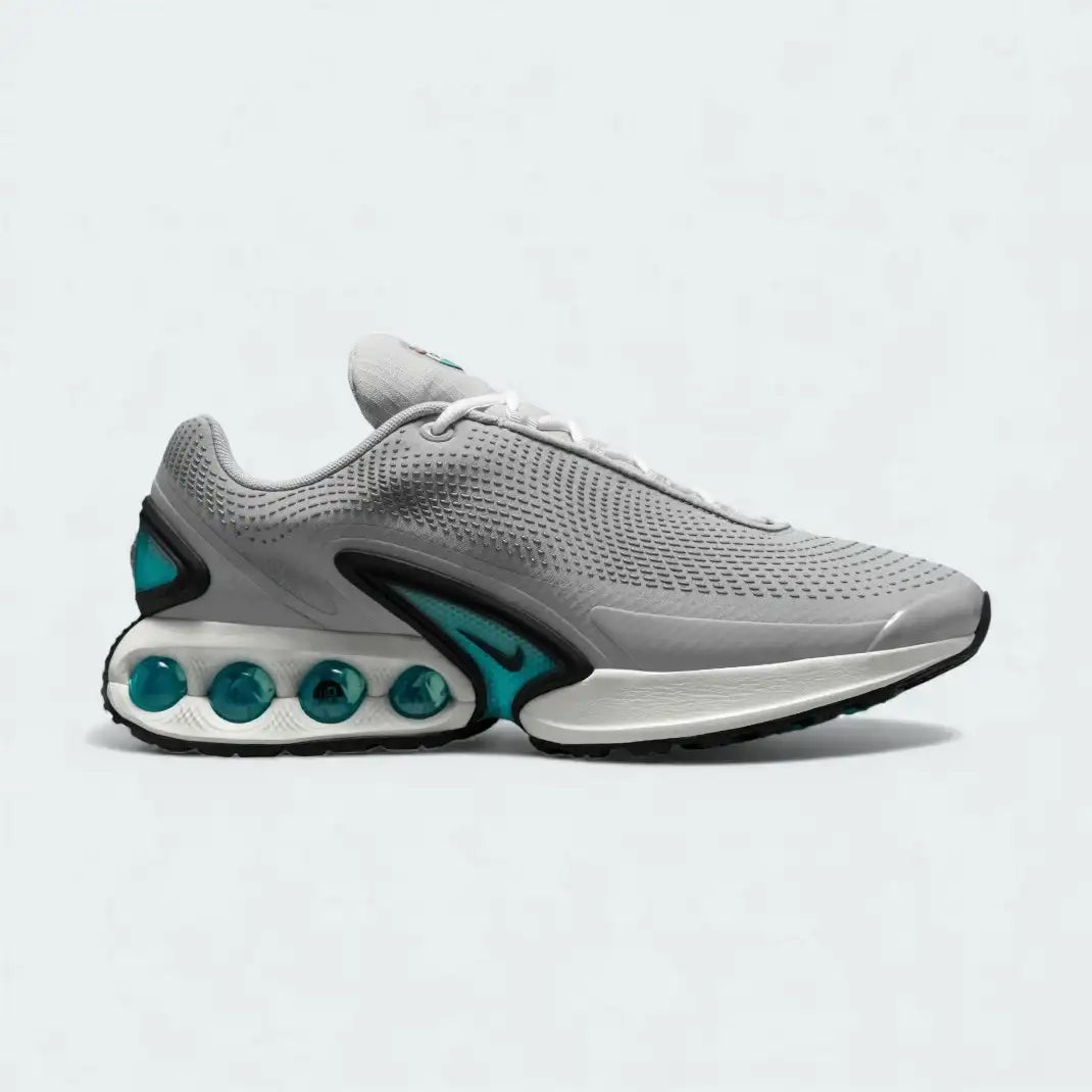 Nike Air Max DN Men's running shoes in light smoke grey and black, side profile showing visible Dynamic Air unit in the heel, textured upper, and sleek silhouette.