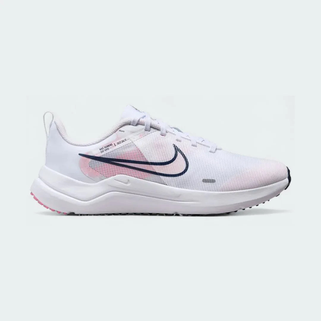Nike Downshifter 12 Premium Women's training shoes in white with metallic gold accents, side profile showing mesh upper, foam cushioning, and Nike Swoosh.