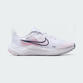 Nike Downshifter 12 Premium Women's training shoes in white with metallic gold accents, side profile showing mesh upper, foam cushioning, and Nike Swoosh.