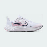 Nike Downshifter 12 Premium Women's training shoes in white with metallic gold accents, side profile showing mesh upper, foam cushioning, and Nike Swoosh.