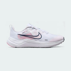 Nike Downshifter 12 Premium Women's training shoes in white with metallic gold accents, side profile showing mesh upper, foam cushioning, and Nike Swoosh.