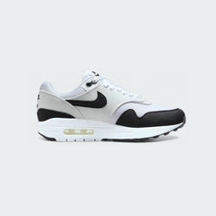 Nike Air Max 1 Women's running trainers in white with light grey and black accents, side profile showing visible Max Air unit in the heel, layered upper, and classic Nike Swoosh.