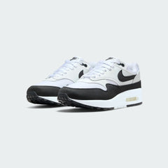 Angled view of two Nike Air Max 1 Women's white running trainers, side by side, showcasing their classic design and visible Air unit.