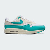 Nike Air Max 1 Women's trainers in white with a dusty cactus blue-green Swoosh, side profile showing visible Max Air unit in the heel and a layered mesh and synthetic leather upper.
