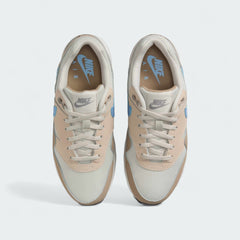 Top-down view of a pair of Nike Air Max 1 Juniors' trainers in light brown and blue, highlighting their classic silhouette and lace-up closure.