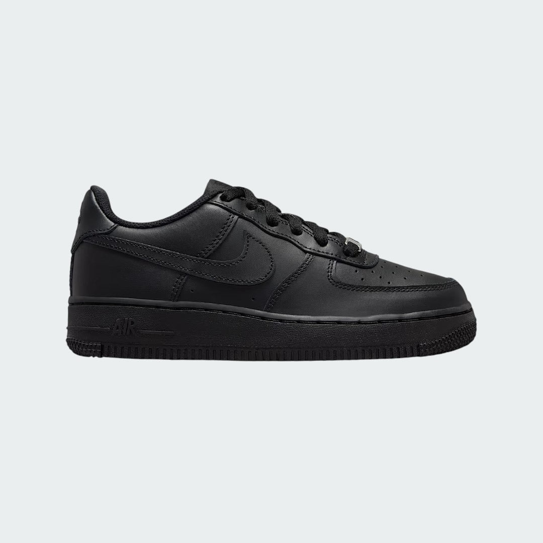 Nike Air Force 1 Juniors' trainers in black leather, side profile showing classic leather upper, perforated toe box, and Nike Swoosh.