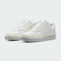 Angled view of two Nike Court Vision Lo Next Nature Women's trainers in white and white, side by side, showcasing their clean aesthetic and retro style.