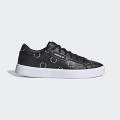 Adidas Originals Sleek Women's trainers in white, side profile showing the all-over black monogram Trefoil logo print on the leather upper.