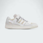 Adidas x Ivy Park Forum Low women's trainers in cloud white, side profile showing leather upper, classic Three Stripes, and hook-and-loop ankle strap.