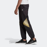 Adidas Tolima 02 Men's Track Pants in black nylon, front view showing elastic waistband, drawcord, side pockets, and classic Adidas 3-Stripes down the legs.