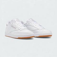 Angled view of two Reebok Classic Club C 85 Unisex white trainers, side by side, showcasing their timeless aesthetic and classic court design.