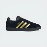 The Core Black Bellingham Gazelle, highlighting the Gold Metallic 3-Stripes and the Jude Bellingham logo on the lateral side.