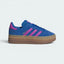 Highlights the high-velocity sweep of the Purple Burst serrated 3-Stripes, the professional gold-foil Gazelle text, and the striking visual grid of the triple-stacked platform rubber outsole.