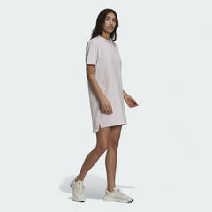 Adidas Tennis Luxe Tee Dress Women's in ambient blush pink, front view on a model, showing its relaxed, oversized fit, ribbed crew neck, and short sleeves.