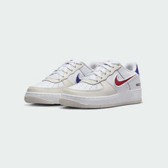 Angled view of two Nike Air Force 1 LV8 Juniors' white trainers with royal blue and red accents, side by side, showcasing their timeless design and clean aesthetic.