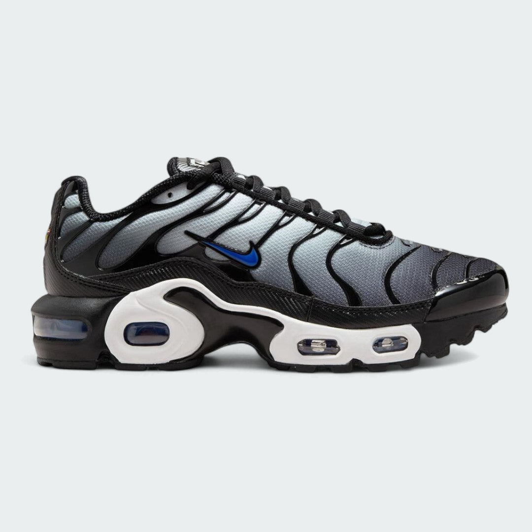 Nike Air Max Plus TN Juniors' trainers in white with racer blue and black accents, side profile showing visible Tuned Air units and distinctive wavy overlays.