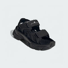 Front angled view of the Adidas by Stella McCartney Hika Sandals in black, focusing on the heel strap and branding.