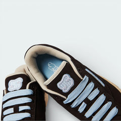 Top-down view of the collab trainers, highlighting the premium suede texture, white lacing, and the embroidered "S" logo on the tongue.