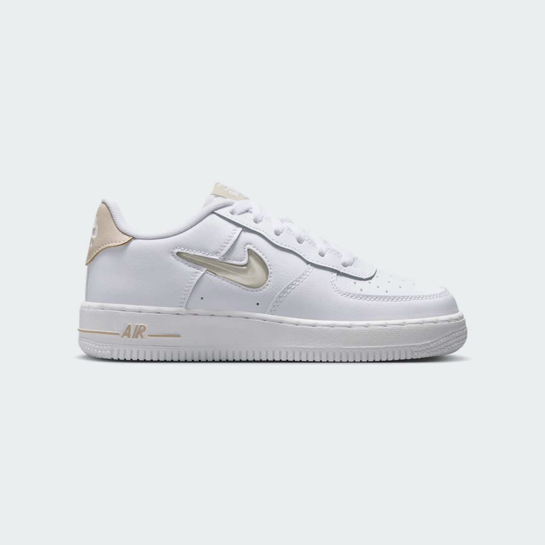Nike Air Force 1 Low Juniors' trainers in white and sand colors, side profile showing classic leather upper, perforated toe box, and Nike Swoosh.