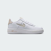 Nike Air Force 1 Low Juniors' trainers in white and sand colors, side profile showing classic leather upper, perforated toe box, and Nike Swoosh.