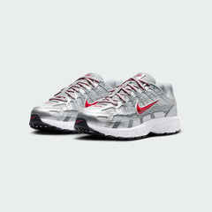 Angled view of two Nike P-6000 Juniors' silver trainers, side by side, showcasing their chunky, retro-inspired aesthetic and layered construction.
