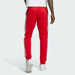 Adidas Superstar Track Pants Men's in red, back view showcasing the tapered leg fit and ribbed cuffs.
