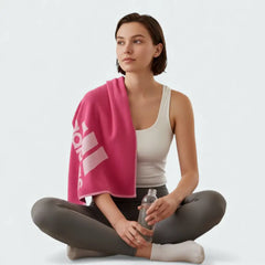 Adidas Cotton Sports Towel in pink, resting on the side of a lady who have been taking part in yoga