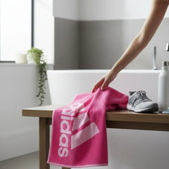 Adidas Cotton Sports Towel in pink, person reaching out to grab it after a workout